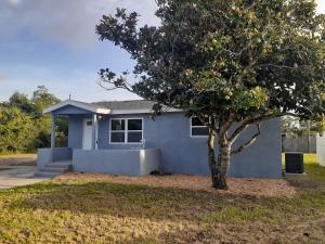 a blue house with a tree in front of it at The Cocoa Cove in Cocoa