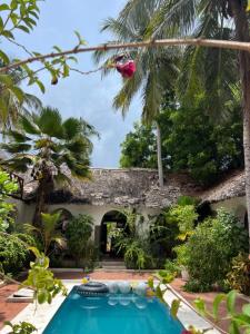 a garden with a swimming pool in front of a house at Kimulimuli Wellness Spa Hotel in Bwejuu