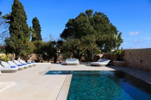 a swimming pool with white chairs and trees at Mansión Santa María in Santa Maria del Camí