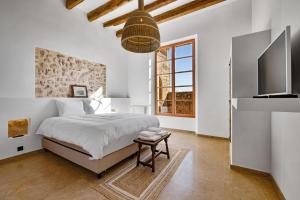 a white bedroom with a bed and a television at Mansión Santa María in Santa Maria del Camí
