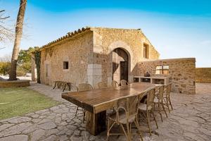 a wooden table and chairs in front of a building at Mansión Santa María in Santa Maria del Camí