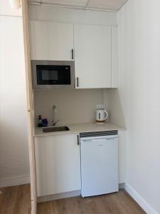 a white kitchen with a refrigerator and a microwave at Albergue Porta Real NO BIKE STORAGE in Santiago de Compostela