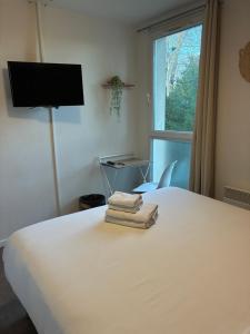 a bedroom with a white bed with towels on it at Hotel Au Bon Sejour in Vitry-le-François