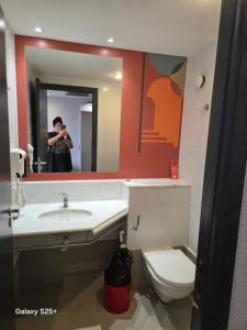 a man taking a picture in a bathroom mirror at Kings Rooms in Luton