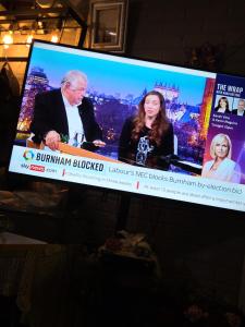 a television screen with two people on it at Kings Rooms in Luton