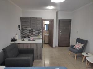 a kitchen and a living room with a couch and chairs at Varkaris Room 2 in Katarráktis