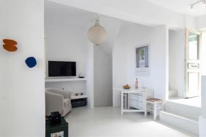 a white living room with a tv and a chair at Blue & Earth Kea in Ioulis