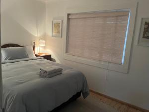 a bedroom with a bed and a window with blinds at The Red door cottage in Pretoria