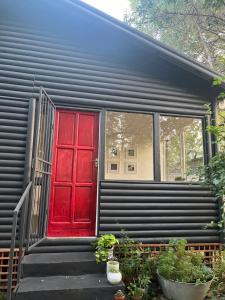 a red door on a black tiny house at The Red door cottage in Pretoria