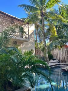 a swimming pool with palm trees next to a house at Casa Nikau Chic Getaway in El Cuyo in El Cuyo