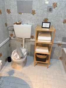 a bathroom with a toilet and a shelf with towels at Studio Central na Amadora, Vista da Cidade, Sossegado, a 15min de Lisboa in Amadora +30 photos