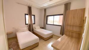 a small bedroom with two beds and a window at RESIDENCE OUARZAZATE in Ouarzazate