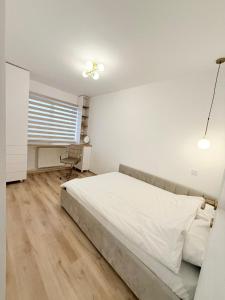a white bedroom with a bed and a desk at Mirajul Modern Apartment - Comfort & Style in Turda