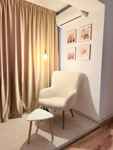 a white chair and a stool in a room at Mirajul Modern Apartment - Comfort & Style in Turda