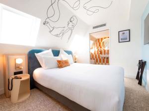ein Schlafzimmer mit einem weißen Bett und einer Treppe in der Unterkunft Mercure Paris Montparnasse Raspail in Paris