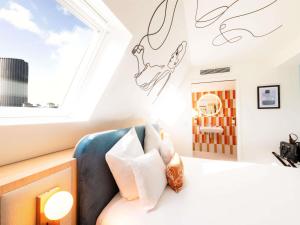ein Schlafzimmer mit einem Bett und einem Fenster in der Unterkunft Mercure Paris Montparnasse Raspail in Paris