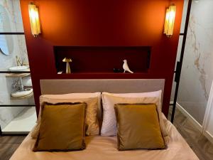 a bed with two pillows and a cat sitting on a red wall at Casa Dos in Hendrik-Ido-Ambacht