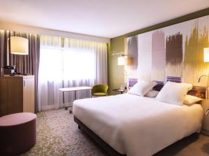 a hotel room with a large white bed and a window at Mercure Reims Parc Des Expositions in Reims