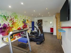 a gym with a treadmill and a colorful wall at Novotel Chartres in Chartres