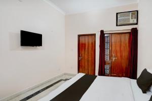 a bedroom with a bed and a flat screen tv at Hotel O Hotel Brijwasi in Lucknow