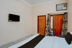 a bedroom with a bed and a tv on the wall at Hotel O Hotel Brijwasi in Lucknow