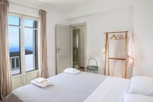 a white bedroom with a large bed and a window at Blue & Earth Kea in Ioulis +17 photos