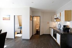 a kitchen with white walls and wooden floors at Apartment MOSELGARTEN - Domherren-Suite in Piesport