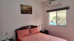 a bedroom with a bed with a red bedspread and a window at Piedra Marina Bahia in Bahía de Caráquez