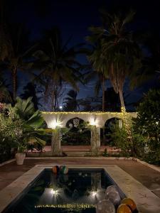 a swimming pool with lights in a yard at night at Kimulimuli Wellness Spa Hotel in Bwejuu