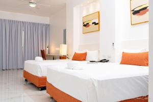two beds in a room with white walls and orange pillows at Stars Hotel Bavaro in Punta Cana
