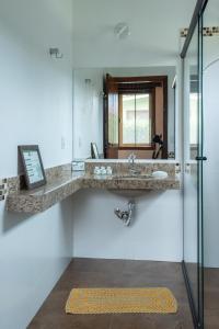 a bathroom with a sink and a mirror at Pousada Alem das Formas in Carrancas +98 photos