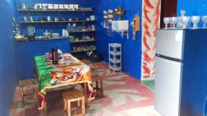 a blue kitchen with a table and a refrigerator at Hostel Mamitchesca in Canoa Quebrada