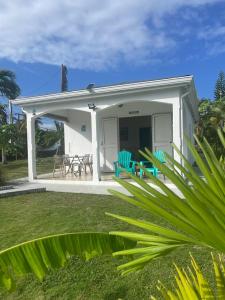 a small white house with two blue chairs in the yard at Coco-orchidées Le Domaine Mannou in Sainte-Rose