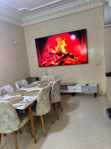 a dining room with a table and a fire on the wall at Apparemment à louer in Derroua +9 photos