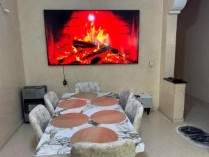 a room with a table and a fire on the wall at Apparemment à louer in Derroua