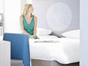 a woman sitting on a bed next to a fan at Novotel Nottingham Derby in Long Eaton +91 photos