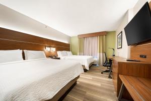 a hotel room with two beds and a flat screen tv at Holiday Inn Express Trincity by IHG in Piarco