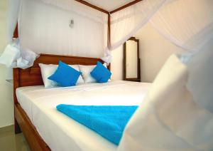 a bedroom with a white bed with blue pillows at Eden Blue Hikkaduwa in Hikkaduwa