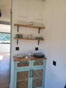 a kitchen with a blue cabinet with plates and glasses at Au Coin du Chêne in Thaon-les-Vosges