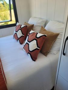 a bed in a room with four pillows on it at Au Coin du Chêne in Thaon-les-Vosges