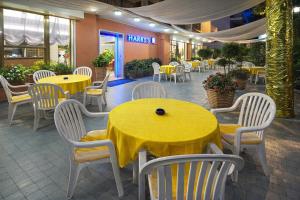 a restaurant with yellow tables and white chairs at Hotel HARRY'S Hospitality Riccione-Fronte Mare in Riccione