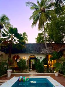 a swimming pool in front of a house with palm trees at Kimulimuli Wellness Spa Hotel in Bwejuu