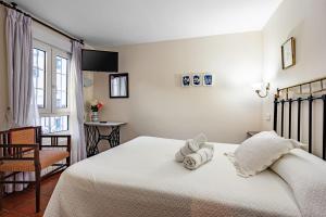 a bedroom with a white bed with towels on it at Apto rurales y habitaciones MONTE CAORU - CABRALES apartahotel in Arenas de Cabrales
