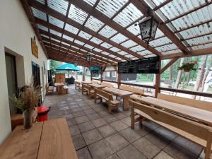 a cafeteria with wooden tables and benches in a building at Chatičky pod Kamínkem Doksy in Doksy