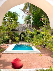 a swimming pool in a garden with an archway at Kimulimuli Wellness Spa Hotel in Bwejuu