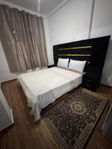a bedroom with a bed with a black headboard and a rug at Dar yasmine in Azrou