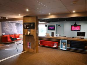 a lobby with a waiting room with a red couch at ibis Laval Le Relais D'Armor in Laval