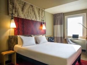a large white bed in a room with a window at Ibis Schiphol Amsterdam Airport in Badhoevedorp
