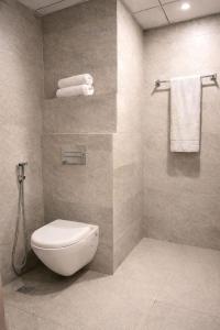a bathroom with a toilet and a shower with towels at StayScape studio in Greater Noida +3 photos