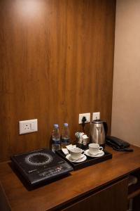 a table with a coffee maker and two cups and water bottles at StayScape studio in Greater Noida